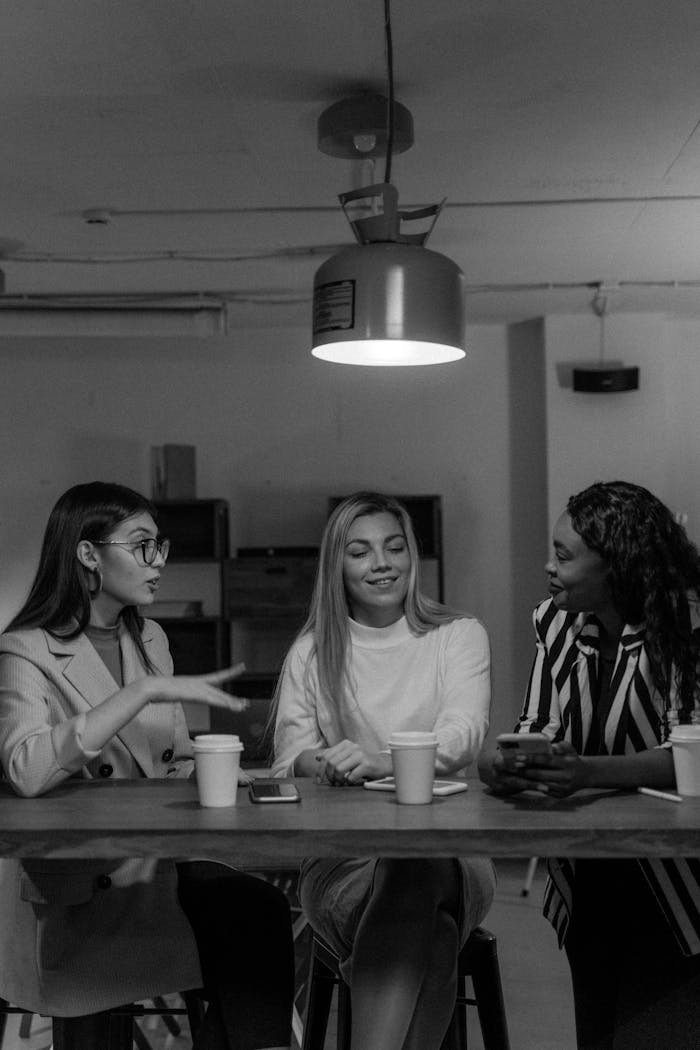 Three diverse businesswomen engaged in a collaborative meeting at a table, fostering creative ideas.